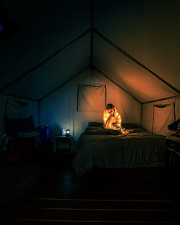 dona, assegut, llit, tenda, campament, llum, persona, manta, llum de nit, suèter, glamping, taronja, fosc, canviant d'humor, nit, relaxant, vacances, fugir, viatjar, vagar, wanderlust, dormitori, a l'interior, llum elèctrica, habitació domèstica, coixí, equips d’il·luminació, còmode, interior de casa, dorment, il·luminat, estils de vida, cap gent, decoració, llum - fenomen natural, relaxació, luxe, casa, mobles, modern, vespre, material de fusta, elegància, apartament, vela, 5K, CC0, domini públic, lliure de regalies