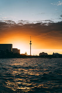 Silhouette von Gebäuden, die Architektur, hinterleuchtet, Strand, Wolken, Dämmerung, Abend, Licht, Ozean, szenisch, Meer, seelandschaft, Himmel, Sonne, Sonnenuntergang, Turm, Wasser, Wellen, orange Farbe, Ufergegend, gebaute Struktur, Schönheit in der Natur, Szenen - Natur, Natur, wolke - himmel, keine Leute, Gebäudehülle, Silhouette, Sonnenlicht, draußen, Gebäude, 5K, CC0, gemeinfrei, lizenzfrei