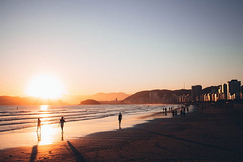 gent, caminar, vora del mar, daurat, hores, retroil·luminat, platja, edifici, núvols, vespre, tarda, hora daurada, paisatge, muntanyes, naturalesa, oceà, a l'aire lliure, reflexions, sorra, mar, paisatge marí, siluetes, cel, sol, posta de sol, aigua, onades, terra, llum solar, arquitectura, bellesa a la natura, cel clar, persones incidentals, reflexió, còpia espai, muntanya, exterior de l'edifici, grup de persones, estructura construïda, 5K, CC0, domini públic, lliure de regalies