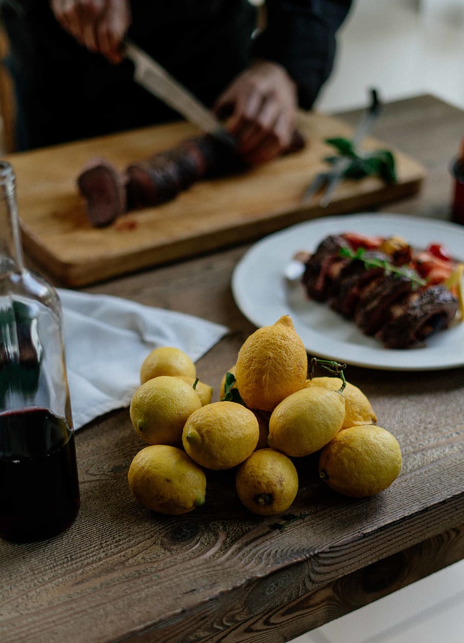 llimones grogues, menjar i beguda, frescor, menjar, persones reals, una persona, a l'interior, taula, alimentació saludable, centrar-se en primer pla, benestar, preparació, secció mitjana, mà humana, cuina, preparar el menjar, homes, mà, fruita, ganivet de cuina, dit, 5K