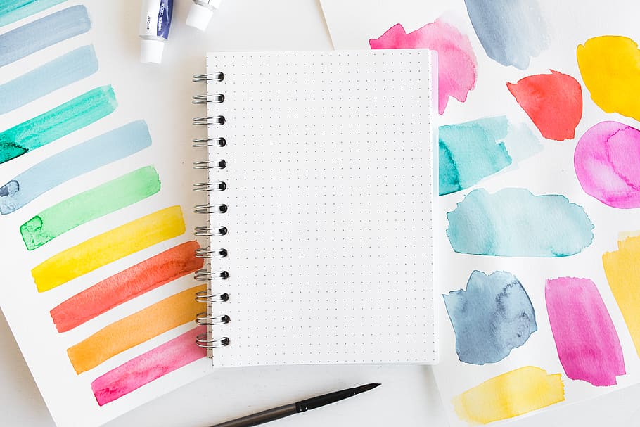 open white notebook, multi colored, art and craft, creativity, indoors, still life, no people, high angle view, table, variation, choice, art and craft equipment, craft, paper, writing instrument, pencil, pen, education, watercolor paints, directly above, close-up, note pad, color swatch, blank, 5K
