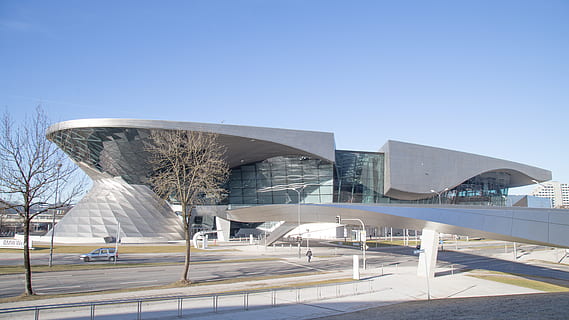 gray concrete building, convention center, building, architecture, person, human, urban, city, town, office building, tent, downtown, transportation, aircraft, airplane, vehicle, metropolis, opera house, planetarium, amphitheatre, amphitheater, built structure, building exterior, clear sky, sky, day, nature, modern, travel destinations, blue, no people, travel, sunlight, outdoors, copy space, tourism, tree, connection, 5K, CC0, public domain, royalty free