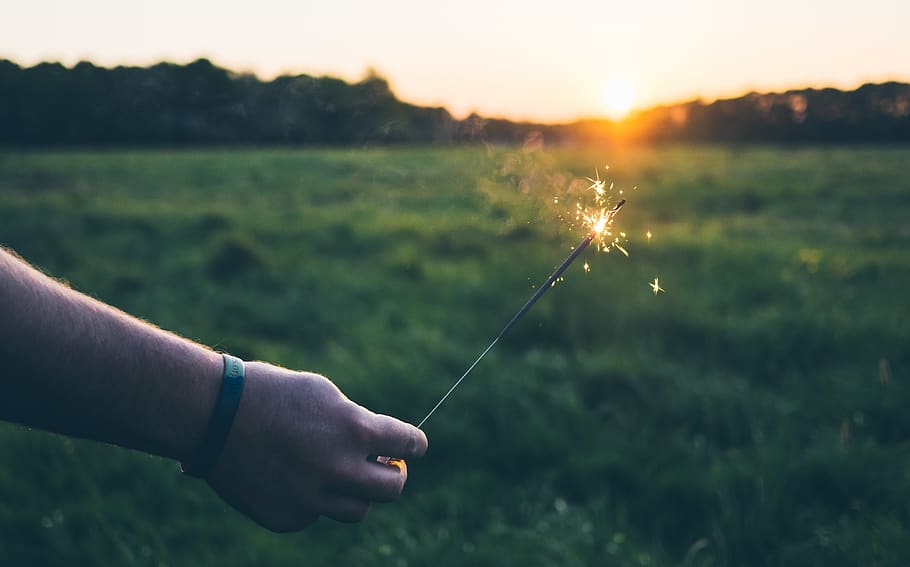 sparkler, llums, foc, flama, mà, verd, herba, camp, naturalesa, a l'aire lliure, parc infantil, paisatge, vista, mà humana, una persona, planta, terra, centrar-se en primer pla, persones reals, part del cos humà, activitat d'oci, celebració, llum solar, posta de sol, cel, homes, dia, sol, flare de la lent, 2K