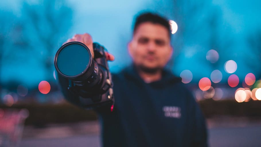 persona, humà, càmera, electrònica, fotografia, foto, cara, fotògraf, mà, rellotge de polsera, moodygram, videògraf, vídeo, director de fotografia, vermell, bokeh, colors, cian, canviant d'humor, una persona, de peu, retrat, vista frontal, celebració, il·luminat, homes, centrar-se en primer pla, mirant la càmera, adult, tecnologia, cintura cap amunt, adult jove, roba casual, mascles, persones reals, activitat d'oci, estils de vida, llum, 5K