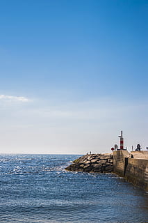 vln, havaroval, mořské zdi, architektura, mraky, scéna s oblaky, pobřeží, denní světlo, horizont, krajina, maják, Příroda, oceán, venku, skály, scénický, moře, přímořská krajina, nebe, kameny, voda, horizont nad vodou, scenics - příroda, krása v přírodě, skupina lidí, pláž, skutečných lidí, přistát, modrý, stavba, den, nábřeží, exteriér budovy, náhodné osoby, 5K, CC0, veřejná doména, bez autorských práv