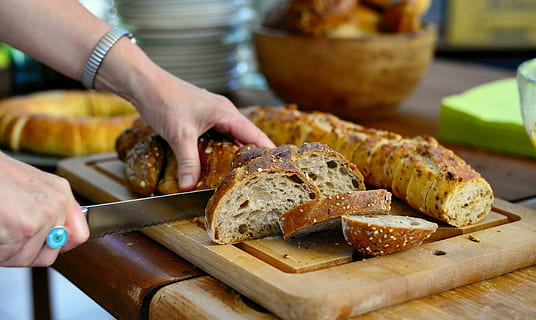 un pan, corte de pan, cortar, rebanadas de pan, junquillo, crujiente, delicioso, desayuno, horneado, panadería, nutrición, bocadillo, comer, comida, mano humana, comida y bebida, mano, una persona, frescura, parte del cuerpo humano, participación, preparación, gente real, tabla de cortar, cuchillo de cocina, adentro, material de madera, de cerca, preparando comida, persona irreconocible, cuchillo, dedo, cuchillo de mesa, 5K, CC0, dominio público, libre de derechos