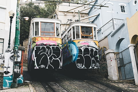 2 tramvies multicolors, vehicle, autobús, transport, pista de tren, ferrocarril, rail, tren, persona, humà, telefèric, contenidor d'enviament, graffiti, tramvia, carro, quiosc, cotxe de càrrega, edifici, barri, urbà, estructura construïda, arquitectura, exterior de l'edifici, dia, cap gent, ciutat, a l'aire lliure, art i artesania, creativitat, funció de construcció de parets, manera de transport, barri residencial, finestra, carrer, art de carrer, multicolor, 4K, CC0, domini públic, lliure de regalies