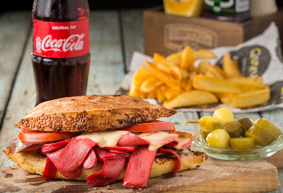 primer pla, fotografia, bun, rodanxes, salsitxa, bacó, desfet, formatge, fons borrós, ampolla, pa, coca-cola, deliciós, menjar, patates fregides, pernil, casolà, carn, adobats, entrepà, llavors de sèsam, saborós, tomàquets, menjar i beguda, frescor, menjar ràpid, llest per menjar, centrar-se en primer pla, fruita, menjar poc saludable, hamburguesa, vegetals, taula, cap gent, dia, natura morta, text, berenar, vidre, 5K