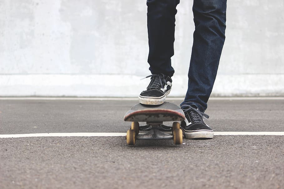 man riding skateboard, apparel, clothing, shoe, footwear, skateboard, sport, person, human, sports, jeans, pants, highway, vans, youth, sneakers, street, shoes, denim, tarmac, asphalt, low section, human leg, body part, road, human body part, one person, real people, city, day, lifestyles, standing, transportation, outdoors, road marking, casual clothing, symbol, leisure activity, human foot, human limb, 5K