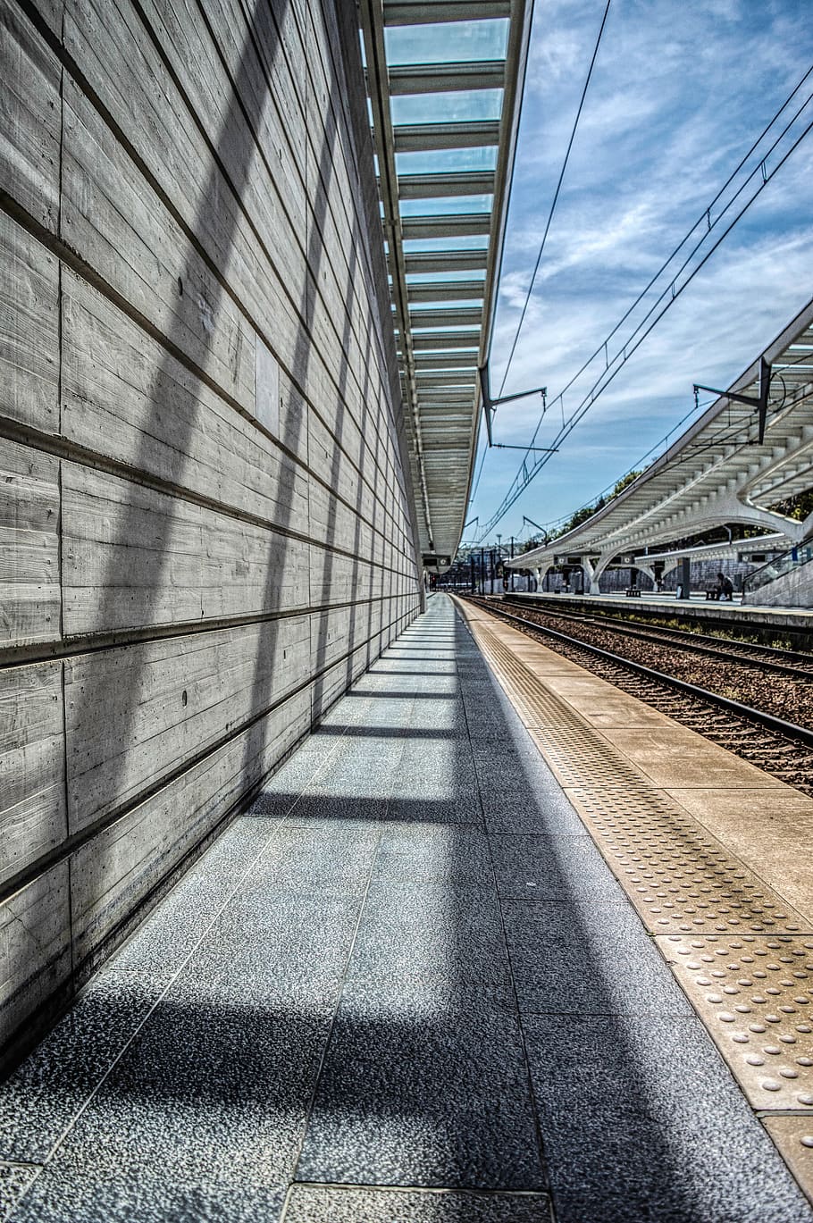 gris, tren ferroviari, durant el dia, transport, terminal, tren, estació de tren, vehicle, persona, humà, ferrocarril, pista de tren, rail, metro, pont, edifici, passadís, Camí, maó, passarel·la, patró, edifici d'oficines, tren bala, arquitectura, estructura construïda, dia, exterior de l'edifici, cap gent, llum solar, el camí a seguir, cel, direcció, ombra, naturalesa, a l'aire lliure, transport per ferrocarril, perspectiva decreixent, modern, núvol - cel, barana, buit, llarg, 4K