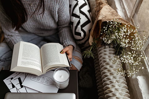 woman, sweater, reads, book, reading, reader, opened book, girl, female, lifestyle, relax, time, candle, pullover, jumper, one person, publication, adult, indoors, women, midsection, holding, hand, human hand, sitting, drink, furniture, human body part, coffee - drink, lifestyles, cup, table, coffee cup, floral pattern, 2K, CC0, public domain, royalty free