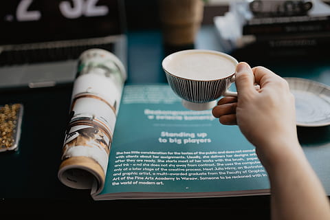reading a magazine, workspace, desk, reading, magazine, time, break, entrepreneur, pause, coffee - drink, human hand, coffee, cup, drink, hand, coffee cup, mug, food and drink, human body part, one person, holding, refreshment, cafe, real people, indoors, focus on foreground, close-up, adult, coffee shop, latte, 5K, CC0, public domain, royalty free