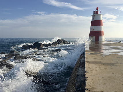 photo, red, white, lighthouse, beach, clouds, horizon, ocean, pier, rocks, sea, seascape, seashore, shore, sky, splashing, water, waves, guidance, horizon over water, motion, wave, tower, beauty in nature, scenics - nature, nature, built structure, architecture, cloud - sky, safety, day, no people, outdoors, power in nature, breaking, 2K, CC0, public domain, royalty free