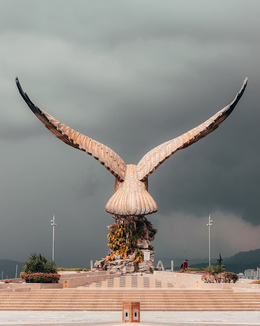šedá socha ptáka, budova, architektura, zvíře, pták, člověk, osoba, létající, město, městský, metropole, stavební jeřáb, věž, kostelní věž, pilíř, sloupec, dav, památník, chrám, mrak - nebe, nebe, stavba, Příroda, den, nikdo, exteriér budovy, venku, umění a řemesla, strom, destinace, rostlina, cestovat, bouřka, sochařství, cestovní ruch, 4K