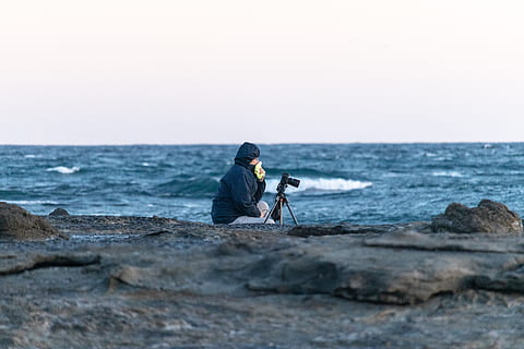 juru potret, kamera, tripod, samudra, foto, fotografi, teknologi, peralatan, orang, laut, air, satu orang, horison, cakrawala di atas air, langit, pantai, tanah, kegiatan waktu luang, padat, duduk, batu, batu - benda, alam, orang sungguhan, keindahan di alam, aktivitas, fokus selektif, di luar rumah, tudung - pakaian, pakaian hangat, 5K, CC0, domain publik, bebas royalti