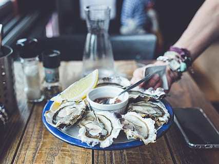fresh, oysters, lemon, citrus, dinner, dish, lunch, meal, oyster, plate, restaurant, sea, seafood, shellfish, food and drink, food, freshness, table, human hand, hand, one person, glass, healthy eating, wellbeing, human body part, indoors, citrus fruit, focus on foreground, ready-to-eat, holding, tray, 4K, CC0, public domain, royalty free