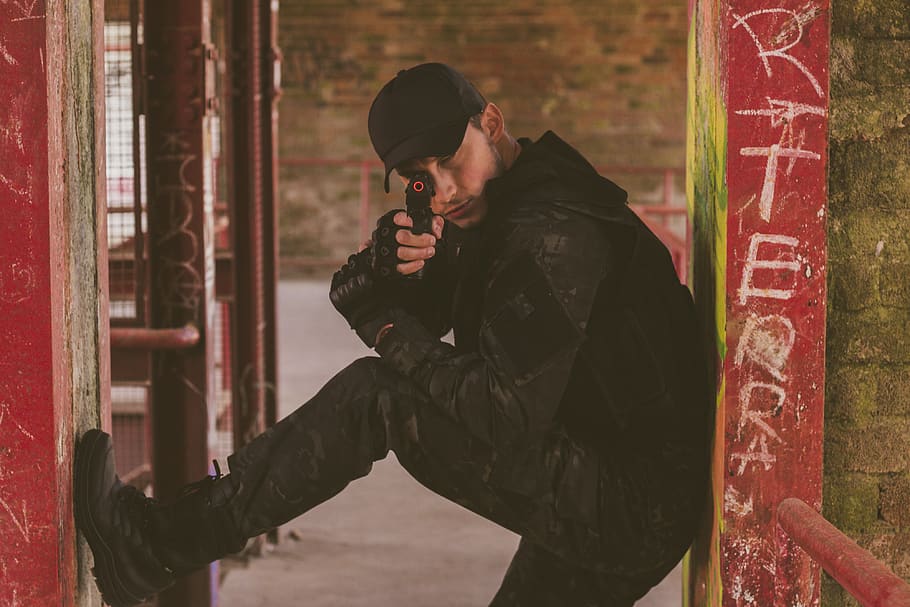 uomo che tiene la pistola, berretto, avvicinamento, uomo, posa, pistola giocattolo, urbano, vandalismo, indossare, giovane, persone reali, una persona, capi di abbigliamento, comunicazione, giovane adulto, vista laterale, stili di vita, giovani uomini, uomini, in piedi, attività di svago, giorno, detenzione, tre quarti, maschi, architettura, segnale di pericolo, arma, vestiti caldi, all'aperto, contemplazione, 4K