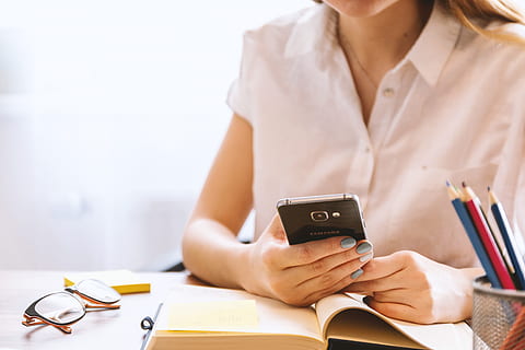 young, woman, uses, smartphone, office, holding, one person, adult, technology, indoors, women, business, wireless technology, copy space, communication, mobile phone, occupation, table, furniture, connection, young adult, human hand, human body part, sitting, hand, 5K
