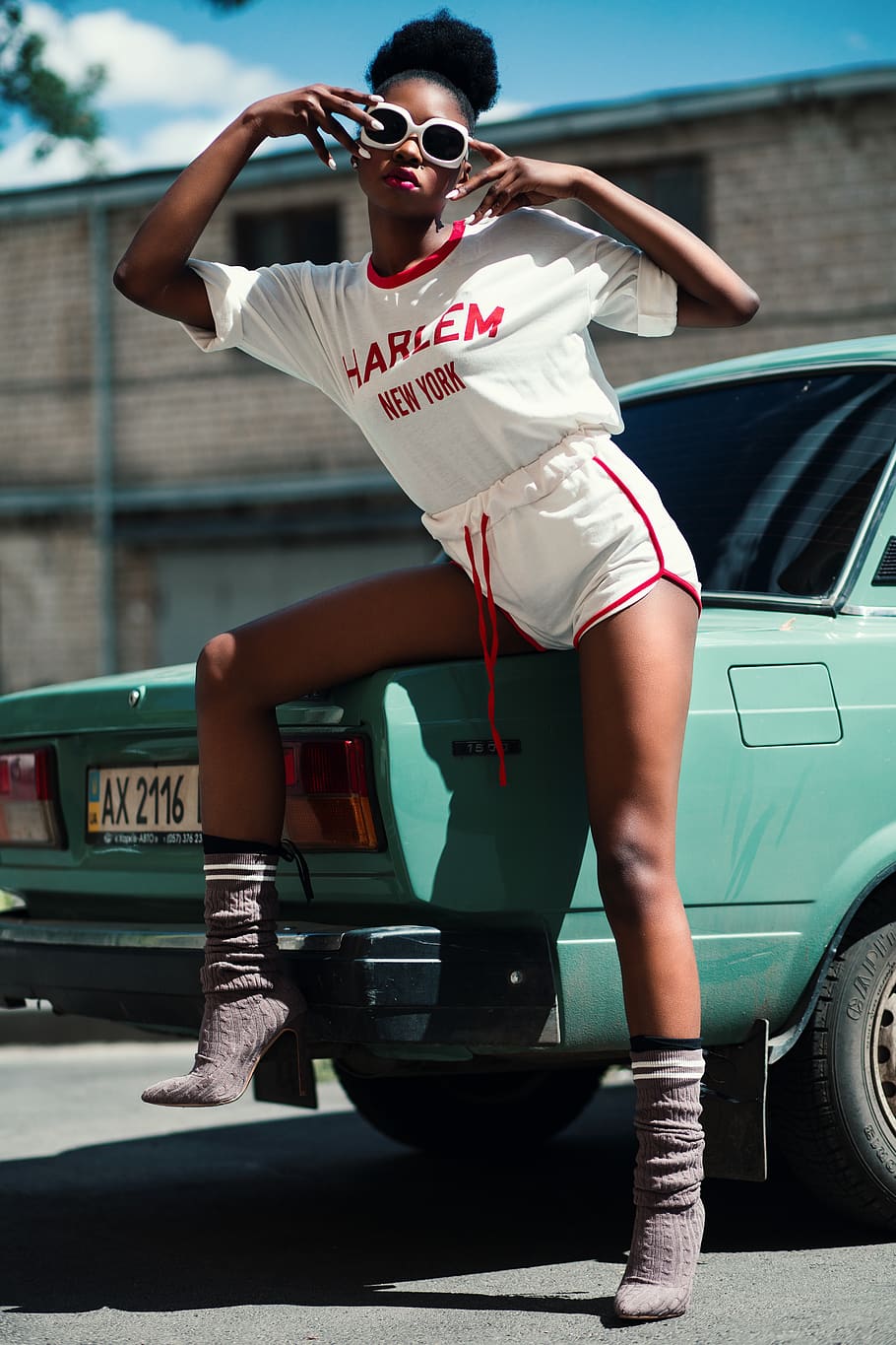 dona, vestit de harlem, edifici, cotxe, núvols, durant el dia, noia, model, pose, carretera, assegut, carrer, ulleres de sol, vehicle, vintage, desgast, jove, manera de transport, persones reals, moda, transport, automòbil, una persona, estils de vida, longitud completa, adult jove, dia, vista frontal, vehicle terrestre, roba casual, gots, activitat d'oci, dones joves, a l'aire lliure, 5K