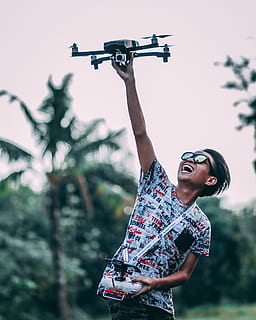 man, holding, quadcopter drone, controller, active, aircraft, drone, enjoyment, fun, smiling, one person, leisure activity, real people, lifestyles, casual clothing, young adult, front view, focus on foreground, standing, day, three quarter length, technology, photography themes, plant, looking away, nature, outdoors, human arm, monopod, 4K, CC0, public domain, royalty free