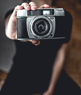 persona, kas tur kameru, antikvariāts, kameru, klasika, elektronika, makro, kameras - fotoiekārtas, fotografēšanas tēmas, tehnoloģijas, fotografēšana, darbību, saimniecība, viens cilvēks, nodarbošanās, telpās, lēca - optiskais instruments, fotografēšanas iekārtas, pieaugušais, koncentrēties uz jaunajām zināšanām, skats no priekšas, tuvplāns, retro stils, roka, slr kamera, digitālā kamera, moderns, fotogrāfs, melns fons, 4K, CC0, publiskais domēns, bez atlīdzības