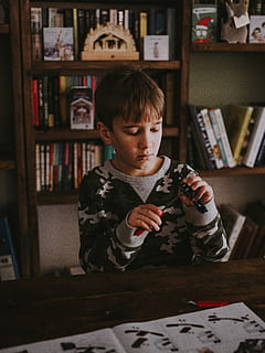 jongen achter de tafel, meubilair, boekenkast, plank, boek, menselijk, persoon, divan, bed, hout, stapelbed, kast, hardhout, multiplex, nachtleven, scherm, tonen, elektronica, LCD scherm, monitor, een persoon, binnenshuis, mannetjes, jongens, mannen, kinderjaren, echte mensen, kind, publicatie, interieur, casual kleding, vooraanzicht, levensstijlen, vrijetijdsbesteding, bezit, boekenplank, onschuld, aan het studeren, 8K, CC0, publiek domein, royaltyvrij