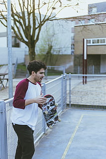 man met skateboard, menselijk, persoon, kleding, shorts, leuning, baluster, skateboard, sport-, sport, mouw, traliewerk, bevloering, lange mouw, broek, tennisbaan, hek, hoed, pet, jas, een persoon, echte mensen, architectuur, buitenkant van het gebouw, drie kwart lengte, ingebouwde structuur, levensstijlen, dag, casual kleding, stad, staand, jonge volwassene, bezit, jonge mannen, vrijetijdsbesteding, zijaanzicht, mannen, straat, boom, buitenshuis, 5K, CC0, publiek domein, royaltyvrij