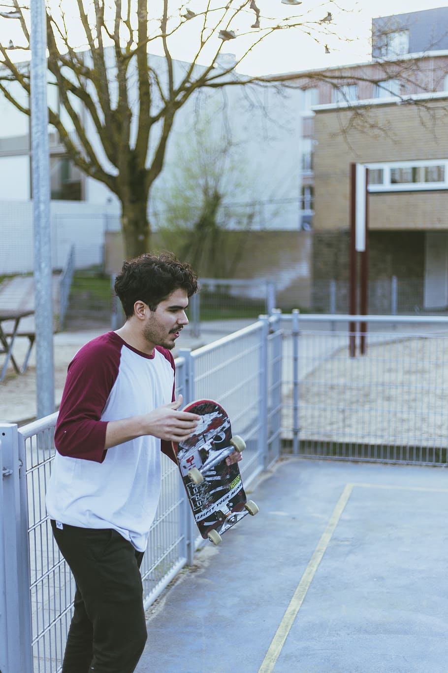 man met skateboard, menselijk, persoon, kleding, shorts, leuning, baluster, skateboard, sport-, sport, mouw, traliewerk, bevloering, lange mouw, broek, tennisbaan, hek, hoed, pet, jas, een persoon, echte mensen, architectuur, buitenkant van het gebouw, drie kwart lengte, ingebouwde structuur, levensstijlen, dag, casual kleding, stad, staand, jonge volwassene, bezit, jonge mannen, vrijetijdsbesteding, zijaanzicht, mannen, straat, boom, buitenshuis, 5K