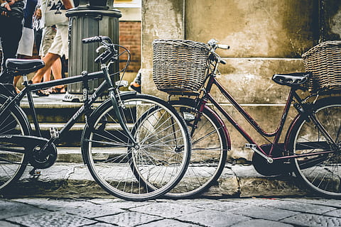 two, black, bicycles parting, wall, baskets, bicycles, city, cityscape, daytime, people, road, street, transportation system, urban, wheels, bicycle, transportation, land vehicle, mode of transportation, basket, architecture, day, bicycle basket, container, stationary, building exterior, footpath, built structure, sidewalk, outdoors, no people, parking, travel, 5K, CC0, public domain, royalty free