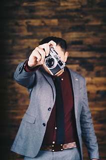 uomo, detenzione, fotocamera mirrorless, telecamera, elettronica, persona, umano, abbigliamento, capi di abbigliamento, fotografia, foto, cappotto, ritratto, fotografo, completo da uomo, viso, giacca, blazer, dito, flettere, film, macchina da presa, macchina fotografica - attrezzatura fotografica, temi fotografici, Fotografare, una persona, tecnologia, attività, persone reali, attività di svago, attrezzatura fotografica, occupazione, vista frontale, abbigliamento casual, in piedi, in casa, stili di vita, uomini, concentrarsi sulle conoscenze acquisite, Camera digitale, 5K, CC0, dominio pubblico, privo di copyright