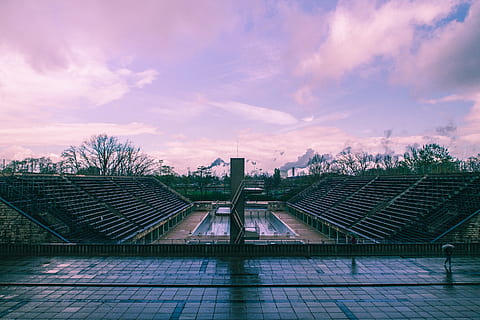 photography of stadium, architectural design, architecture, clouds, light, modern, outdoors, sky, skyline, stadium, steel, trees, urban, cloud - sky, built structure, building exterior, nature, no people, city, roof, sunset, building, plant, tree, solar energy, sport, dusk, high angle view, environment, day, 2K, CC0, public domain, royalty free