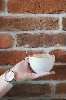 maó, paret, paret de maó, fons, cafè, tassa, tassa de cafè, tassa de café, cappuccino, mà, celebració, noia, femella, tassa blanca, mà humana, una persona, temps, part del cos humà, persones reals, veure, funció de construcció de parets, rellotge de polsera, estils de vida, part del cos, dit humà, dit, dones, menjar i beguda, rellotge, extremitat humana, 5K, CC0, domini públic, lliure de regalies