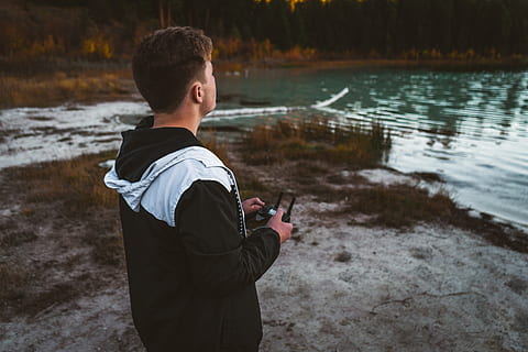 om, deținere, controler de dronă, persoană, uman, îmbrăcăminte, haine, apă, natură, în aer liber, plantă, copac, Electronică, fotograf, fotografie, ședință, maneca, deget, aparat foto, teren, maneca lunga, pantaloni, oameni adevărați, o persoana, lac, stiluri de viață, Activitatea de agrement, tehnologie, bărbați, tehnologia fără fir, comunicare, zi, să se concentreze asupra primelor elemente, permanent, haine casual, telefon inteligent, Barbat tanar, 5K, CC0, domeniu public, fără drepturi de autor