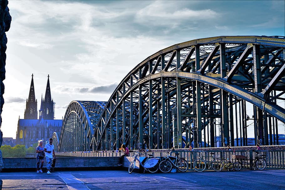 bro, koln tyskland, arkitektur, bygget struktur, transport, ekte folk, bygge eksteriør, menn, forbindelse, by, himmel, gruppe med folk, bro - menneskeskapte struktur, reise, reisemål, tilfeldige mennesker, sky - himmel, transportmiddel, bygning, mennesker, utendørs, 8K