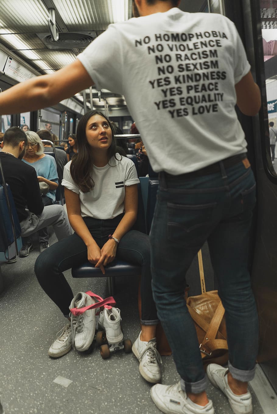 woman, wearing, white, crew-neck shirt, black, jeans, sitting, train seat, commute, commuters, equality, fashionable, footwear, Get Real, Get Real Movement, people, public, public transportation, roller skates, t-shirt, train, transportation system, vehicle, wear, real people, two people, casual clothing, men, togetherness, full length, transportation, mode of transportation, incidental people, seat, front view, shoe, women, adult, lifestyles, chair, young adult, indoors, 4K