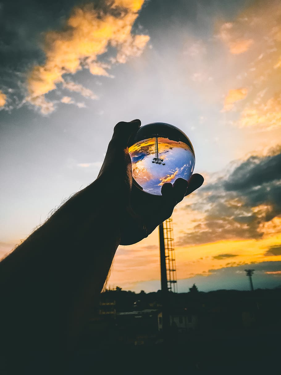 persona, celebració, bola de vidre, retroil·luminat, núvols, alba, la llum del dia, energia, tarda, mà, llum, home, recreació, reflexió, cel, sol, posta de sol, una persona, color taronja, núvol - cel, mà humana, part del cos humà, naturalesa, persones reals, silueta, activitat d'oci, estils de vida, a l'aire lliure, bellesa a la natura, persona irreconeixible, il · lusió óptica, vista d’angle baix, vidre, dit, 4K
