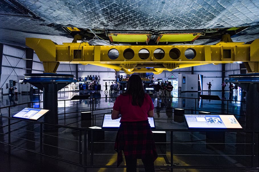 Technik, Wissenschaft, Raumschiff, bemühen, Space Shuttle, echte Menschen, Rückansicht, eine Person, Stehen, Frau, gebaute Struktur, die Architektur, drinnen, Lebensstile, Erwachsene, Freizeitbeschäftigung, Kommunikation, Technologie, Legere Kleidung, Text, Dreiviertel Länge, Gebäude, modern, Decke, Frisur, 5K