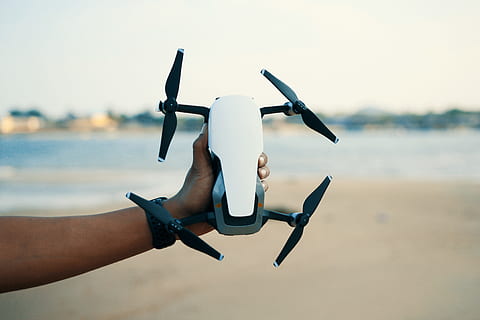 person, holding, white, black, quadcopter drone, camera, drone, macro, technology, human body part, human hand, hand, water, focus on foreground, nature, day, people, limb, adult, sky, human limb, men, body part, outdoors, human arm, two people, 4K, CC0, public domain, royalty free