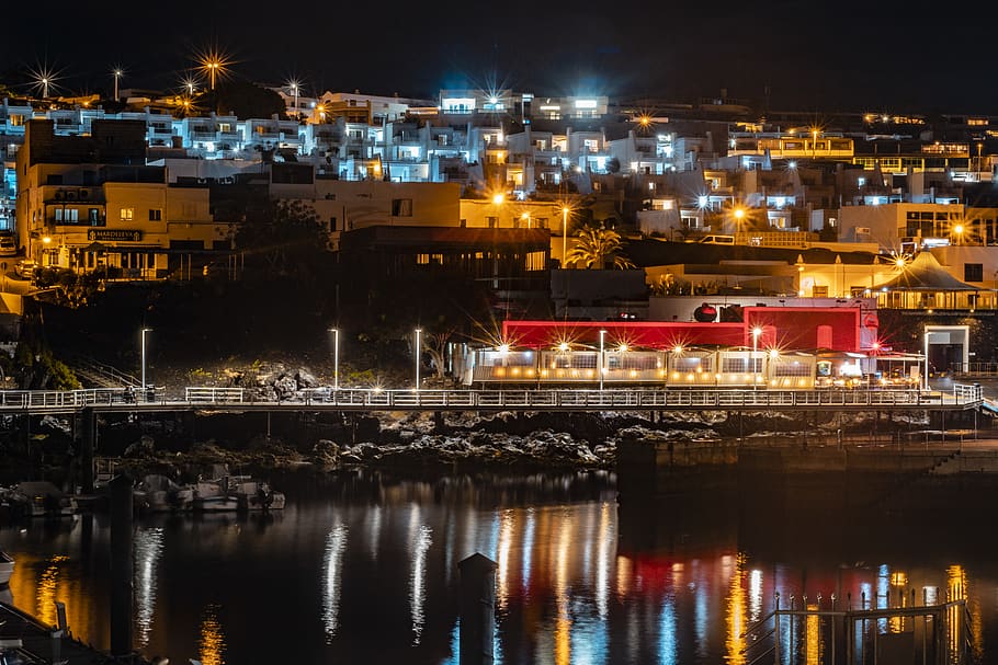 paisatge urbà il·luminat, aigua, davant del mar, moll, port, edifici, puerto del carmen, arquitectura, urbà, marina, ciutat, llum, motos aquàtiques, vaixell, vehicle, transport, cúpula, passeig marítim, pont, exterior de l'edifici, il·luminat, nit, estructura construïda, reflexió, cap gent, riu, naturalesa, barri residencial, a l'aire lliure, paisatge urbà, equips d’il·luminació, brillant, 5K