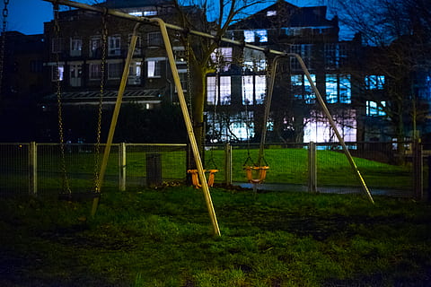 unoccupied swing, swing, park, toy, playground, desolate, unused, dark, night, lonely, run down, decrepit, sad, alley, urban, town, street, road, city, building, alleyway, plant, grass, architecture, built structure, building exterior, no people, nature, field, land, tree, day, outdoors, green color, absence, lawn, outdoor play equipment, 4K, CC0, public domain, royalty free