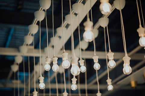 lighted bulbs, lighting, lamp, chandelier, light fixture, crystal, railing, ceiling light, light, sphere, suspenders, lightbulb, lampshade, aisle, indoors, spoke, machine, shop, room, dining room, accessory, no people, hanging, lighting equipment, low angle view, selective focus, illuminated, close-up, decoration, large group of objects, focus on foreground, string, built structure, light bulb, glass - material, ceiling, electric light, abundance, in a row, creativity, electric lamp, 5K, CC0, public domain, royalty free