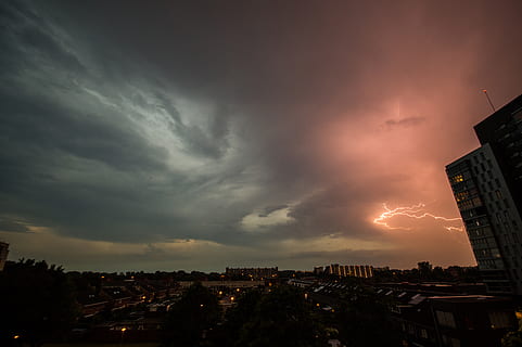 lightning, storm, clouds, cloudy, sky, dark, night, city, cityscape, building exterior, architecture, cloud - sky, built structure, building, nature, no people, residential district, sunset, dramatic sky, storm cloud, outdoors, beauty in nature, thunderstorm, overcast, power in nature, ominous, apartment, 5K, CC0, public domain, royalty free