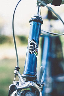bicicleta blava, centrar-se en primer pla, dia, primer pla, metall, cap gent, tecnologia, bicicleta, manera de transport, vehicle terrestre, transport, estacionari, a l'aire lliure, naturalesa, manillar, gestionar, equipament, enfocament selectiu, comunicació, blau, generació de combustible i energia, 5K, CC0, domini públic, lliure de regalies
