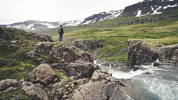 mountains, cliffs, valleys, fields, snow, rocks, water, stream, nature, outdoors, hike, trek, trail, hiker, man, backback, knapsack, backpack, green, grass, mountain, leisure activity, scenics - nature, beauty in nature, hiking, activity, adventure, sky, solid, one person, rock, rock - object, mountain range, full length, tranquility, non-urban scene, travel, lifestyles, snowcapped mountain, 2K, CC0, public domain, royalty free