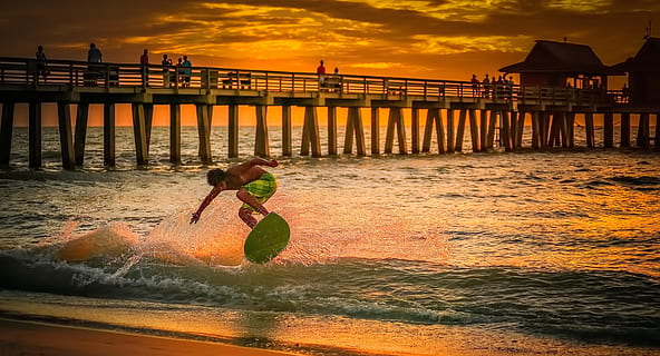 hombre, vistiendo, verde, pantalones cortos de surf, dorado, hora, playa, nubes, muelle, noche, hora dorada, horizonte, paisaje, naturaleza, Oceano, gente, arena, mar, marina, costa, apuntalar, cielo, puesta de sol, tabla de surf, surf, agua, olas, gente real, estilos de vida, actividad de ocio, arquitectura, movimiento, nube - cielo, belleza en la naturaleza, estructura construida, frente al mar, una persona, longitud total, tierra, al aire libre, 2K, CC0, dominio público, libre de derechos