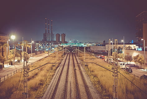 night, dark, train tracks, railroad, railway, buildings, industrial, power lines, cars, vans, street lights, lamp posts, building exterior, architecture, built structure, illuminated, city, transportation, sky, rail transportation, track, railroad track, mode of transportation, nature, street, building, high angle view, no people, skyscraper, train - vehicle, office building exterior, outdoors, cityscape, 720P, CC0, public domain, royalty free