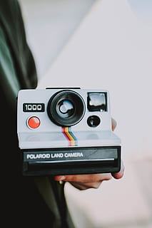 person, holding, gray, polaroid land camera, camera, close-up, device, electronics, equipment, instant camera, lens, modern, object, plastic, polaroid, retro, technology, vintage, wireless, woman, one person, hand, photography themes, human hand, real people, camera - photographic equipment, human body part, photographic equipment, lifestyles, focus on foreground, midsection, men, activity, body part, communication, digital camera, finger, 5K, CC0, public domain, royalty free