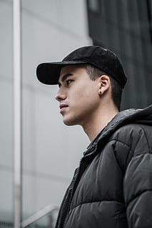 man, black, bubble jacket, apparel, clothing, person, hat, human, cap, jacket, face, coat, portrait, earring, all black, looking out, fashion, style, outdoor, city, model, headshot, one person, young men, real people, young adult, looking away, looking, lifestyles, leisure activity, side view, standing, focus on foreground, architecture, built structure, contemplation, profile view, teenager, 5K, CC0, public domain, royalty free