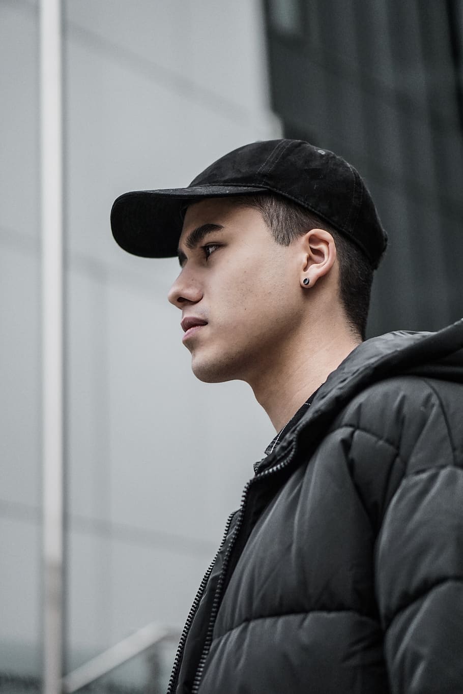mand, sort, boblejakke, beklædning, tøj, person, hat, human, kasket, jakke, ansigt, frakke, portræt, ørering, helt sort, kigger ud, mode, stil, udendørs, by, model, hovedskud, en person, unge mænd, rigtige mennesker, ung voksen, kigger væk, leder, livsstil, fritidsaktivitet, sidebillede, stående, fokus på forgrunden, arkitektur, bygget struktur, overvejelse, profilvisning, teenager, 5K
