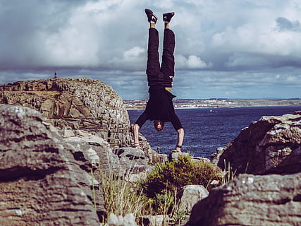 man, wearing, black, dress shirt, burgundy pants hand, standing, rock formations, across, sea, cliff, clouds, grass, handstand, horizon, landscape, nature, ocean, outdoors, rocks, seashore, sky, stones, view, water, waves, rock - object, solid, cloud - sky, rock, real people, land, one person, lifestyles, leisure activity, full length, beauty in nature, day, horizon over water, scenics - nature, 2K, CC0, public domain, royalty free